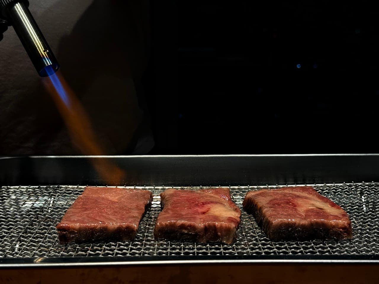 Sliced Japanese Wagyu on a slate platter with aromatics