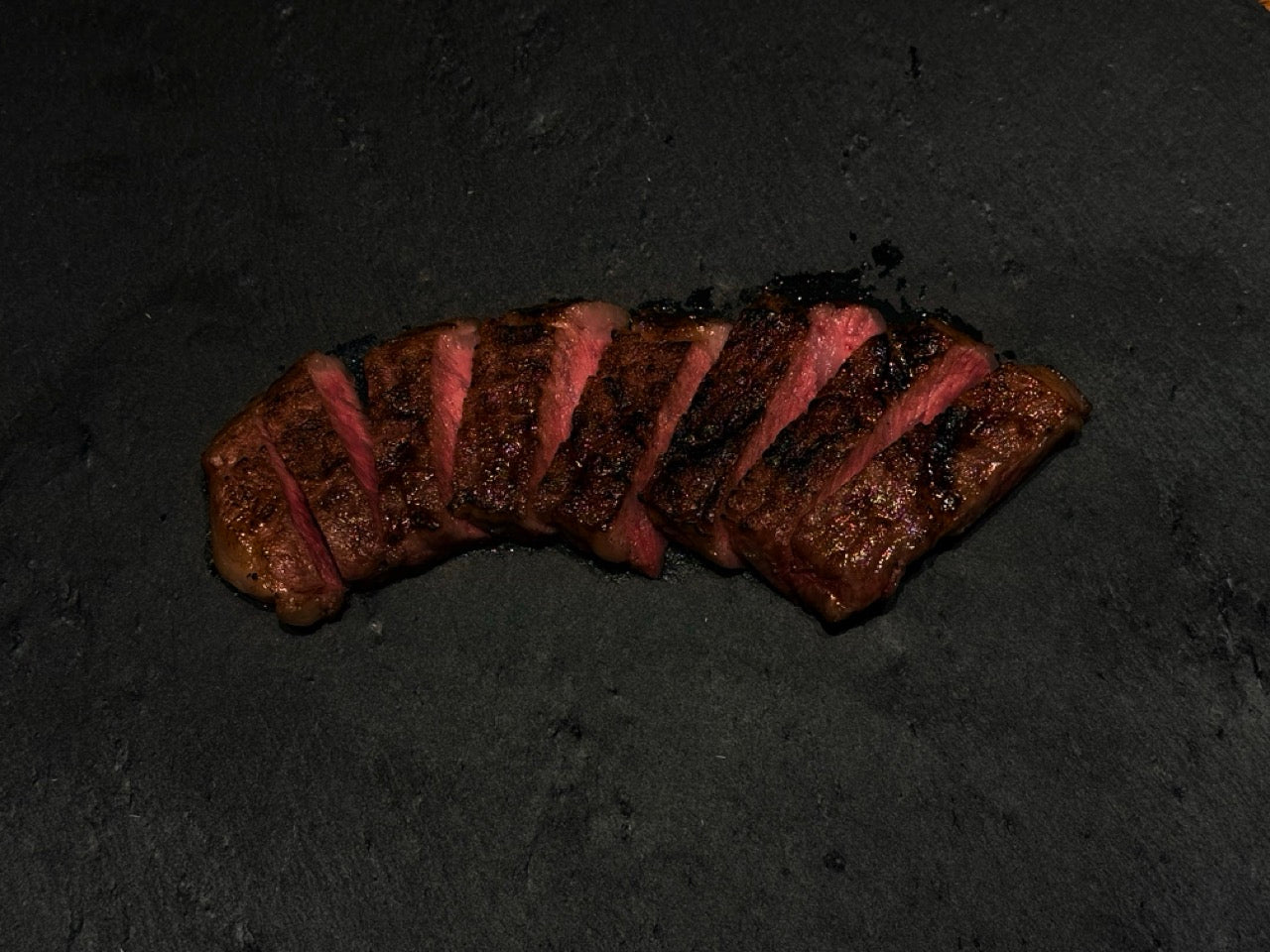 Sliced medium-rare Wagyu steak on a dark slate plate