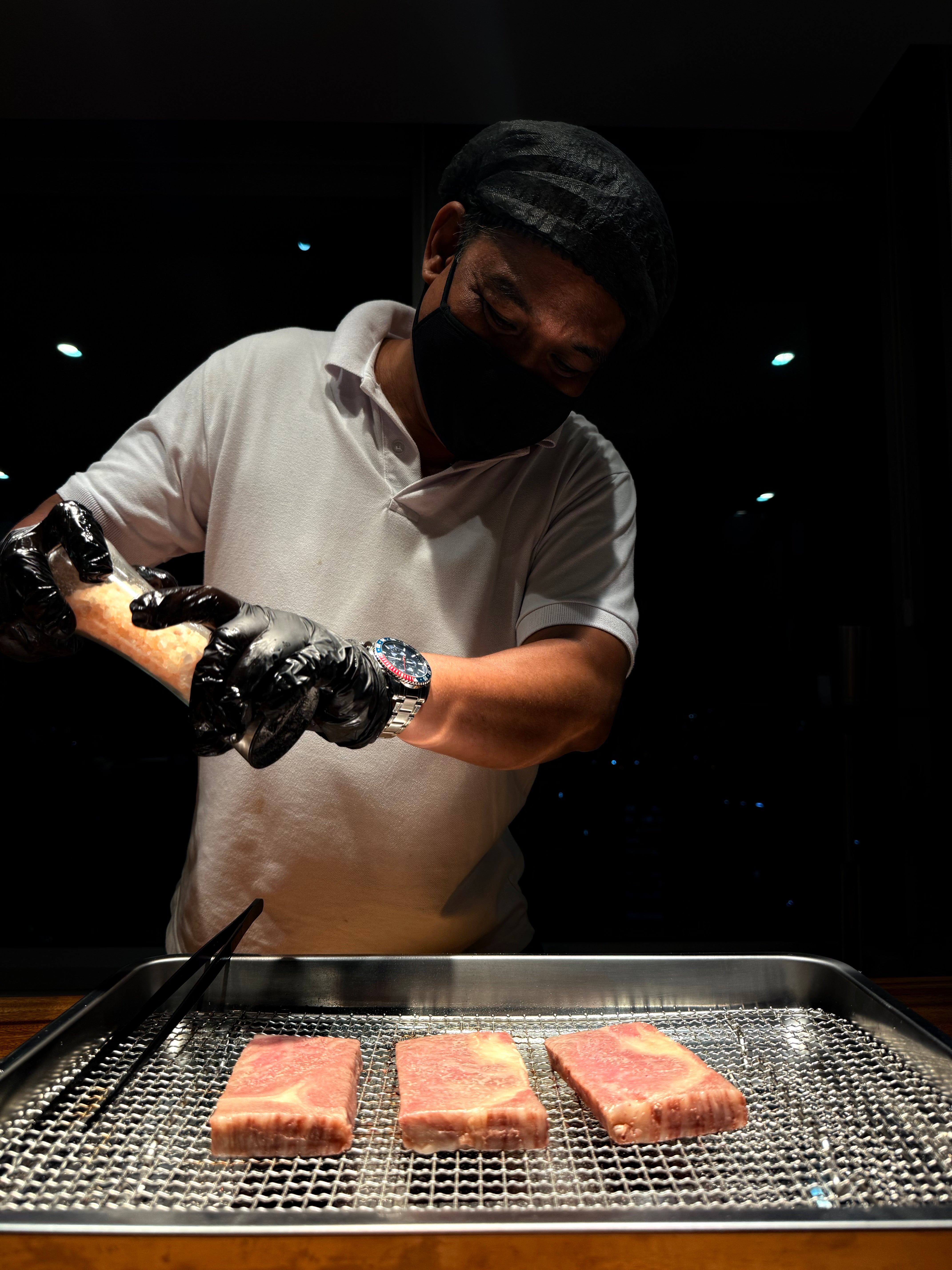 Chef seasoning premium marbled Wagyu steaks in a professional kitchen